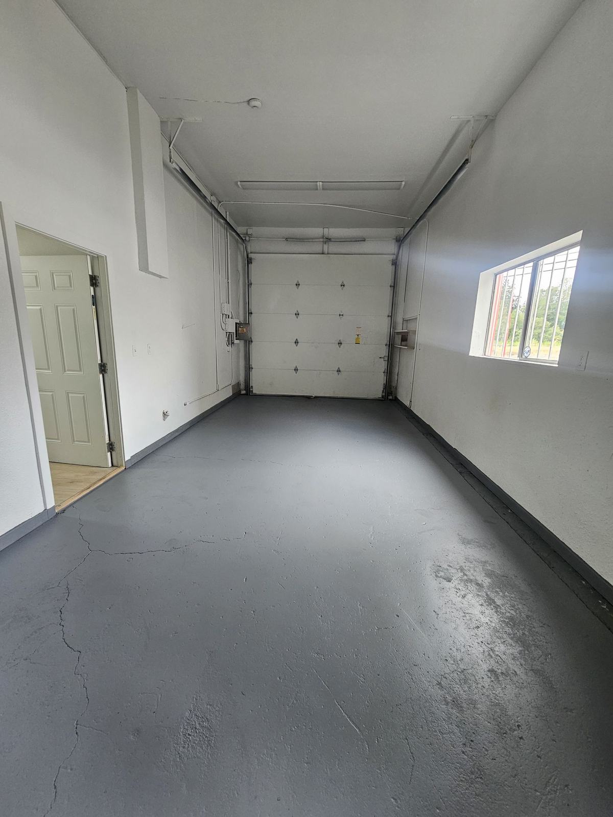 Attached garage shop with rollup door and painted floor